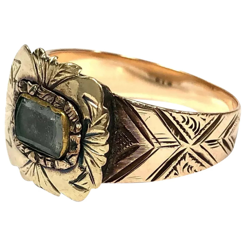 A Victorian Era antique mourning ring with hair displayed beneath a faceted glass crystal.
