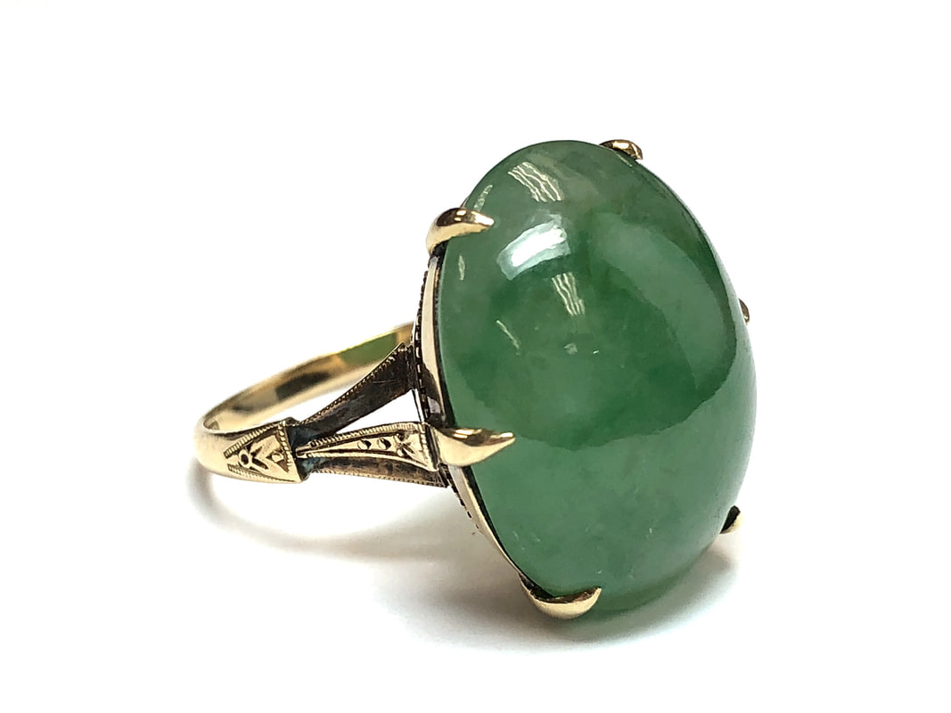 Translucent, mottled green jadeite jade double cabochon in an antique, hand chased gold setting.