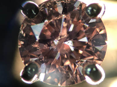 An imperfect diamond in the d to z color range has been coated with a pink surface coating, giving the appearance of a fancy pink diamond