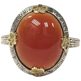 Beautiful carnelian cabochon set in a white gold ring with yellow gold floral prongs